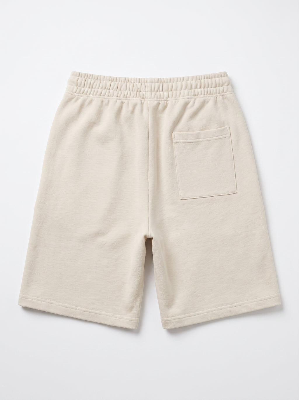 A pair of cream-colored fleece shorts with an elastic waistband and a side pocket, shown from the back on a light gray background.