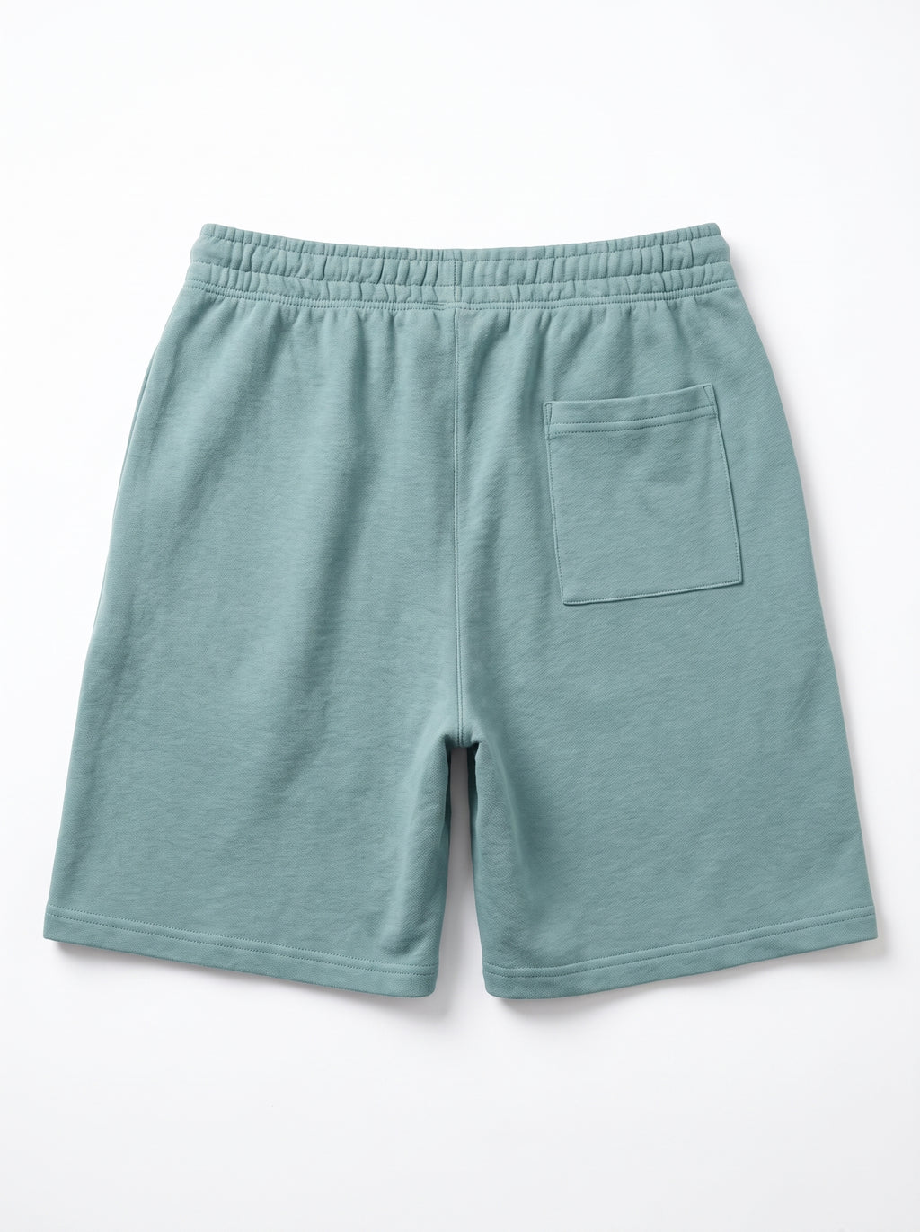 A pair of sage green fleece shorts with an elastic waistband and a single patch pocket on the back, shown flat on a white background.