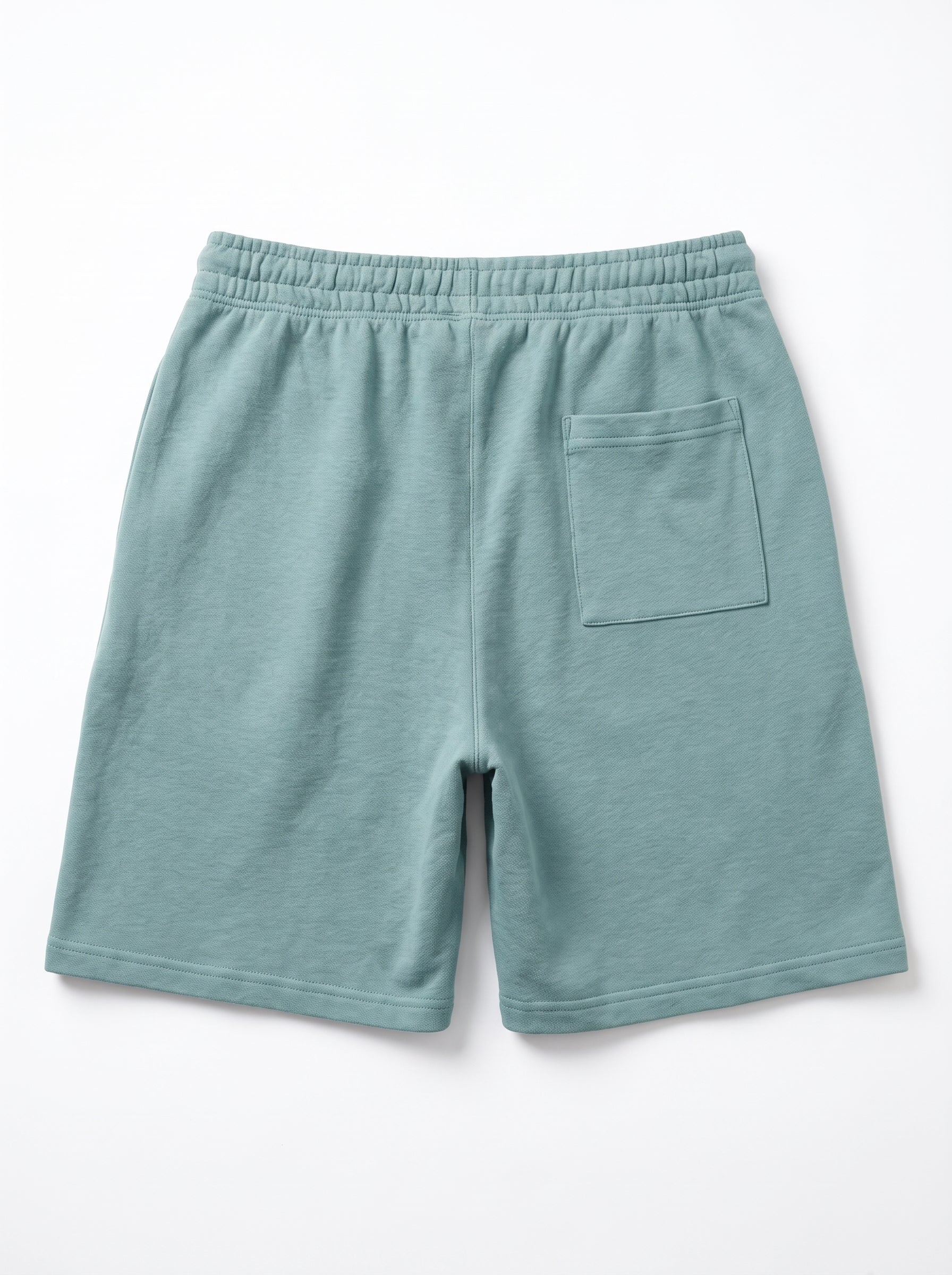A pair of sage green fleece shorts with an elastic waistband and a single patch pocket on the back, shown flat on a white background.