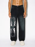 Man wearing White Lotus vintage washed wide leg denim jeans with sunfade graphic and off-white sneakers