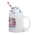 White mug with festive design, whipped cream, and a straw on a white background