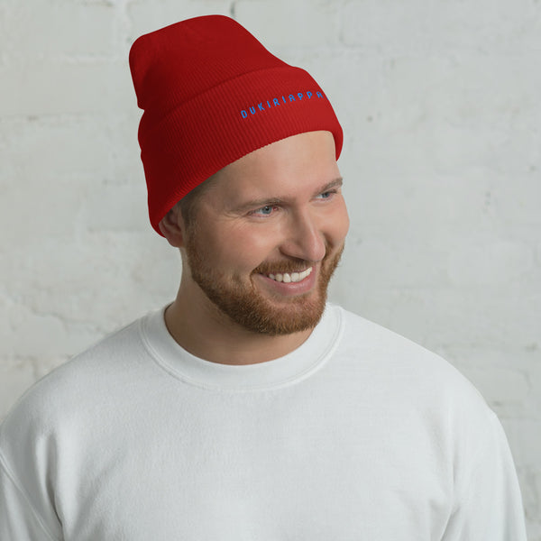 a man wearing a red beanie smiles at the camera